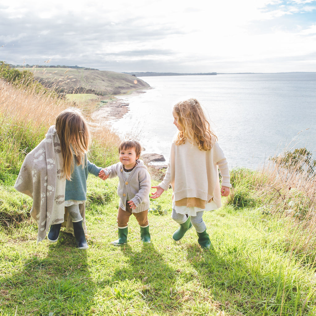three children with personalised blankets with photo of flinders, Mornington Peninsula in the background