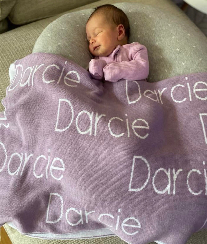 Newborn baby sleeping with a mauve personalised blanket on them